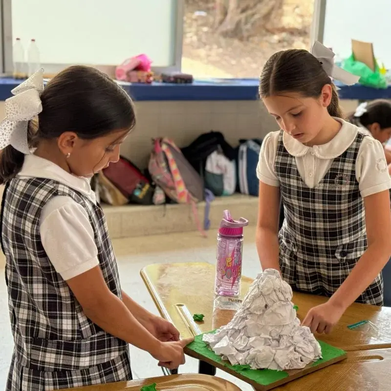 Dos alumnas del instituto trabajan juntas en un proyecto de maqueta con materiales reciclados en el aula